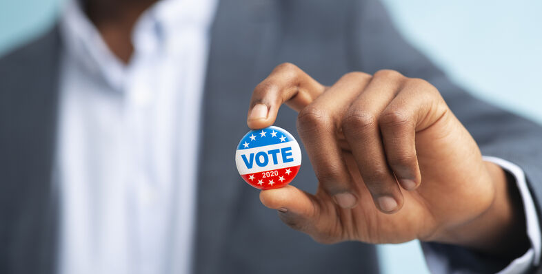 A man holding a VOTE button