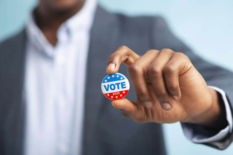 A man holding a VOTE button