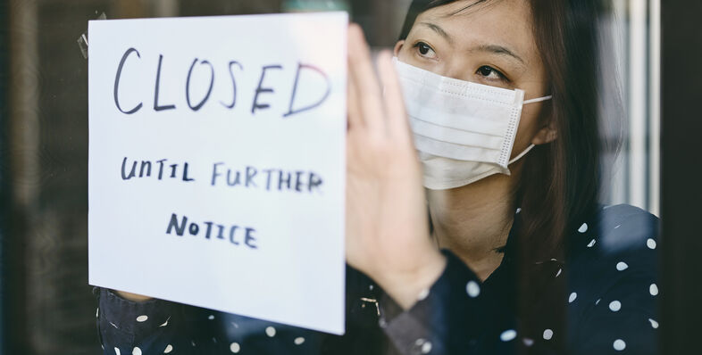 A woman posting a closed sign in a window