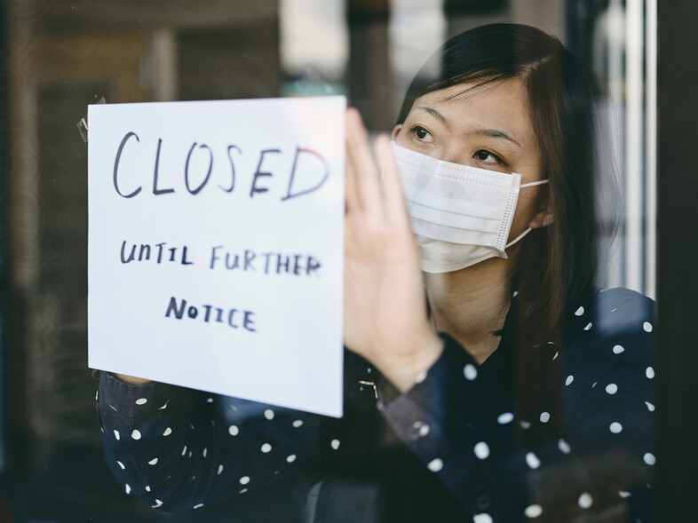 A woman posting a closed sign in a window