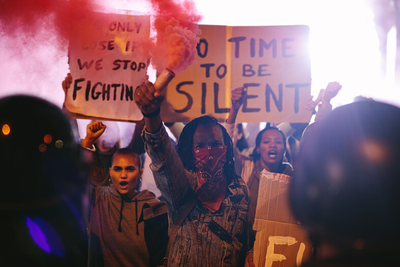 A photo of protesters holding signs and smoke bombs