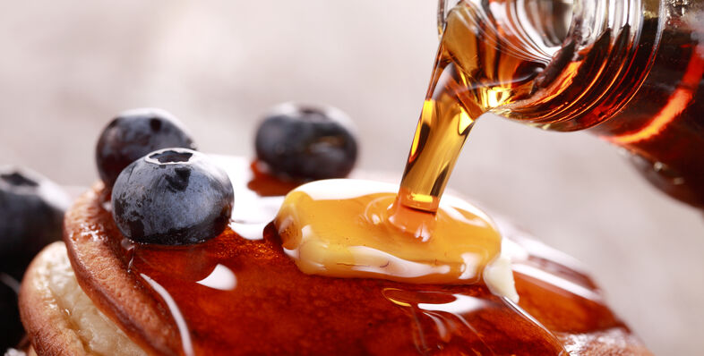 A photo of syrup being poured onto pancakes