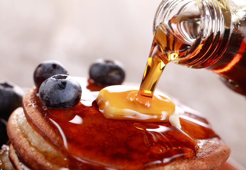 A photo of syrup being poured onto pancakes