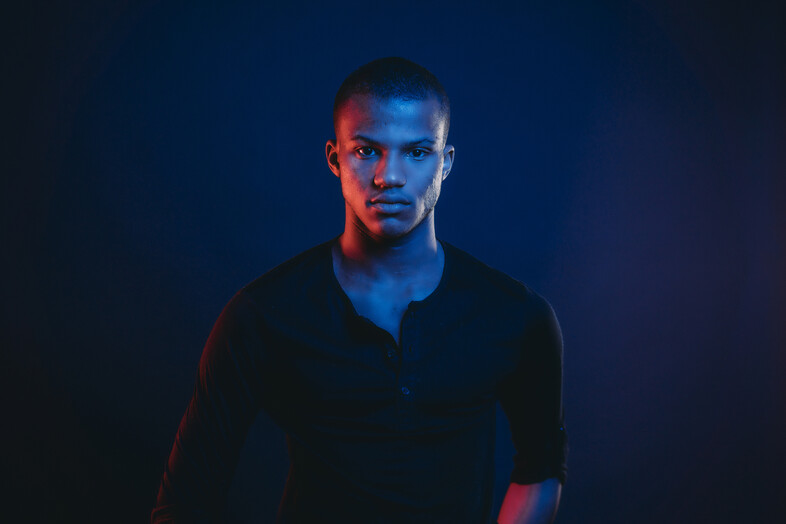 A man in blue light staring at the camera